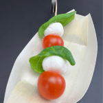 Caprese Spies met tomaat, mozzarella en basilicum in een bamboe bootje in de hapjeskar